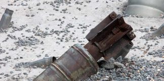 Rusty metal machinery part embedded in gravel and sand