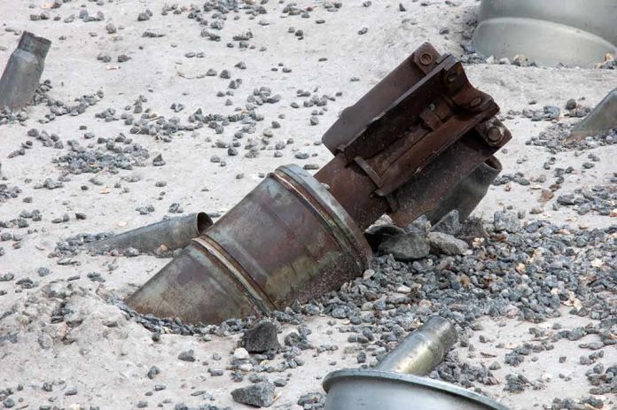 shutterstock_1470397724 Rusty metal machinery part embedded in gravel and sand
