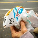 Hands holding a Taco Bell Doritos Locos Tacos