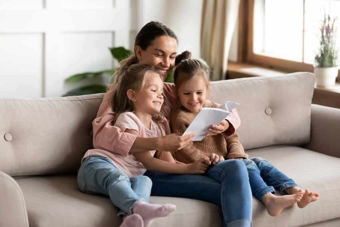 shutterstock_1570353451 Woman reading a book with two young girls on a sofa