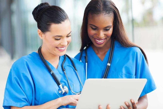 Two nurses in blue scrubs looking at a tablet