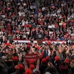 Speaker at podium addressing large crowd in arena