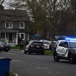 Police SUVs with lights on block a suburban street