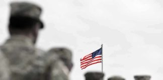 American flag above blurred soldiers in formation