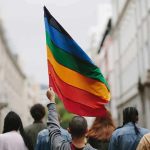 Disgusting Gay Pride Float Sparks OUTRAGE Person holding a rainbow flag in a city street march