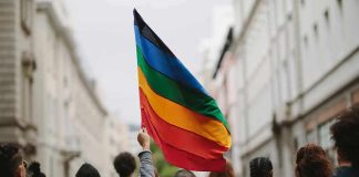 Person holding a rainbow flag in a city street march