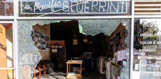 Shopfront with large shattered glass window opening into print shop