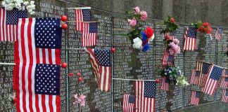 Memorial wall adorned with American flags and flowers