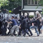 Protesters clash with riot police holding shields