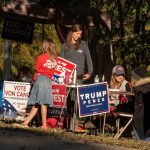 People at a campaign booth with political signs outdoors