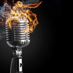 Vintage microphone on fire against a dark background