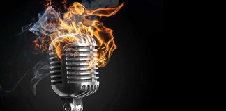 Vintage microphone on fire against a dark background