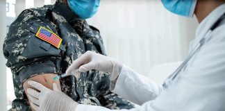 Healthcare worker giving vaccine to person in military uniform