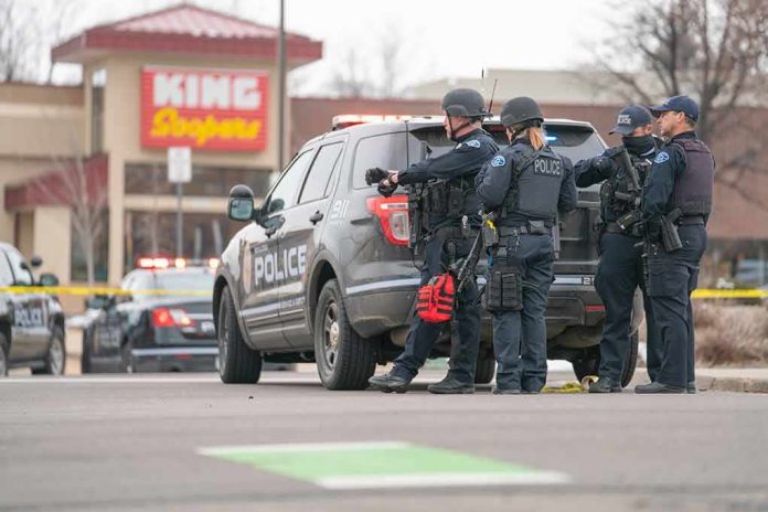 shutterstock_1941371278 Police officers gather beside a patrol SUV at a taped-off scene