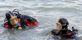 two divers in full-face masks floating in choppy water