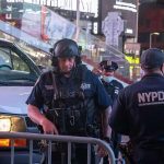 Police officers in tactical gear near a patrol vehicle at night