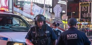 Police officers in tactical gear near a patrol vehicle at night