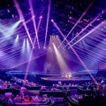 Concert stage with performers under purple laser lights