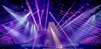 Concert stage with performers under purple laser lights
