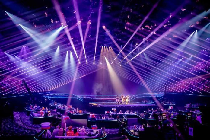 shutterstock_1982762090 Concert stage with performers under purple laser lights
