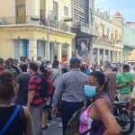 crowd of people wearing masks gathered on a city street