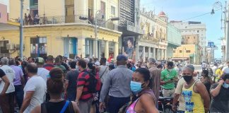 crowd of people wearing masks gathered on a city street