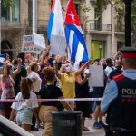 Walter Jones amid crowd at street protest with Cuban flags and police present