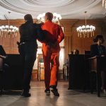 Synagogue Massacre Plot – Teens Nabbed Prisoner in orange jumpsuit escorted by officer in a courtroom
