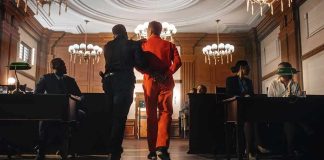 Synagogue Massacre Plot – Teens Nabbed Prisoner in orange jumpsuit escorted by officer in a courtroom