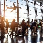Trump DEPORTS Afghan Informant Who Served U.S Passengers queue inside an airport terminal at sunset