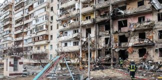 Damaged apartment building behind a playground slide