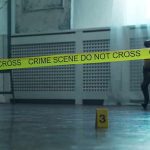 Crime scene tape across a room with evidence marker on floor