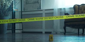 Crime scene tape across a room with evidence marker on floor