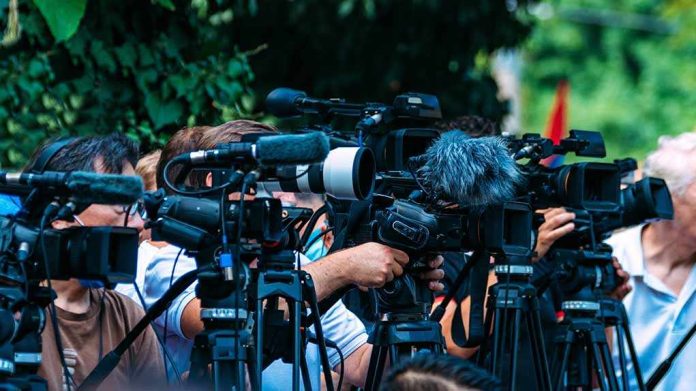 shutterstock_2210577723-1 TV news cameras crowding together at an outdoor event