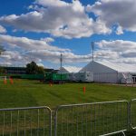 World Cup Fan Zone Turns Deadly! Temporary white tents and equipment on a grassy field with traffic cones and metal barriers