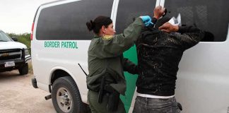 Border patrol agent detains a person against a van