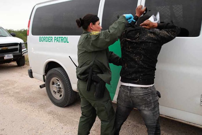 shutterstock_2265137295 Border patrol agent detains a person against a van