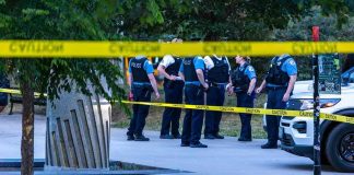 Super Drug Hits Streets – Teen Bodies Appear police officers stand behind caution tape at a park scene