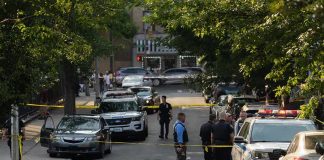 Mom Found Beaten to DEATH Alongside Toddler Police officers secure a residential street with patrol cars and yellow tape