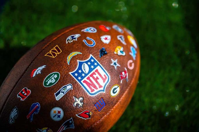 shutterstock_2360209067 Football with NFL shield and team logos on turf
