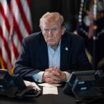 Trump Orders Americans to Pay Their Fair Share Person in suit seated at table with telephones
