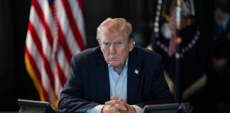Trump Orders Americans to Pay Their Fair Share Person in suit seated at table with telephones