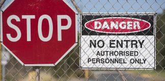 Stop sign and danger no entry sign on chain-link fence