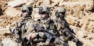 Dontrelle Inman with two other soldiers in tactical gear holding rifles in a rocky desert