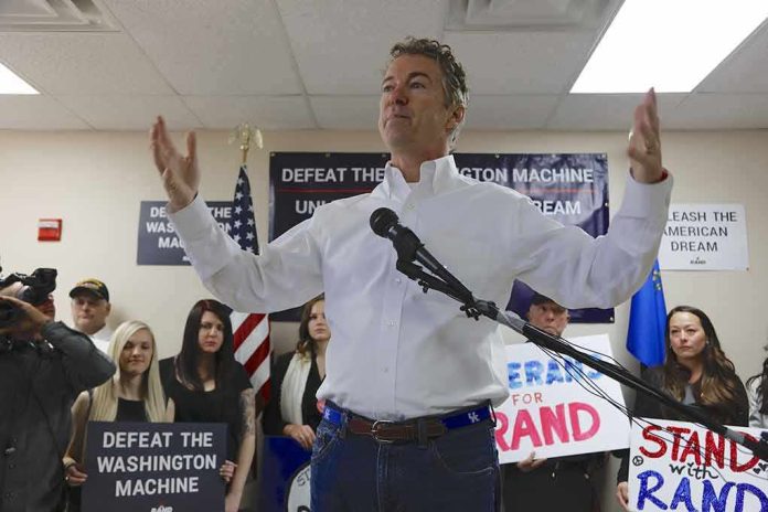 Rand Paul speaking at a campaign event with supporters holding signs