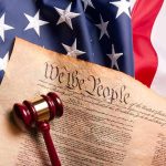 U.S. Constitution with gavel on American flag
