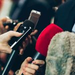 Microphones held up to a speaker in a suit