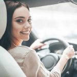 Woman driving a car and smiling over her shoulder