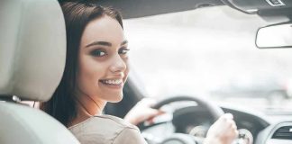 Woman driving a car and smiling over her shoulder