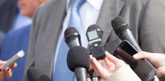 Microphones held toward a person in a suit